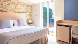 Un dormitorio con una cama grande, un cabecero de madera, una pared de piedra, un escritorio y una silla.