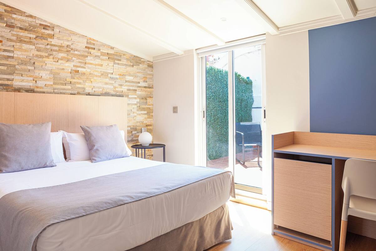 Ein Schlafzimmer mit einem großen Bett, einem Holz-Kopfteil, einer Steinwand, einem Schreibtisch und einem Stuhl.
