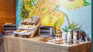 Un bufé de desayuno con una variedad de pasteles, una estación de café y una exhibición de periódicos.