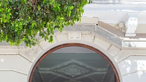 The entrance to a building with a large arched doorway, a sign reading "OLYMPIA CONSUL DEL MAR", and a blue sign with an 'H' indicating a hotel.
