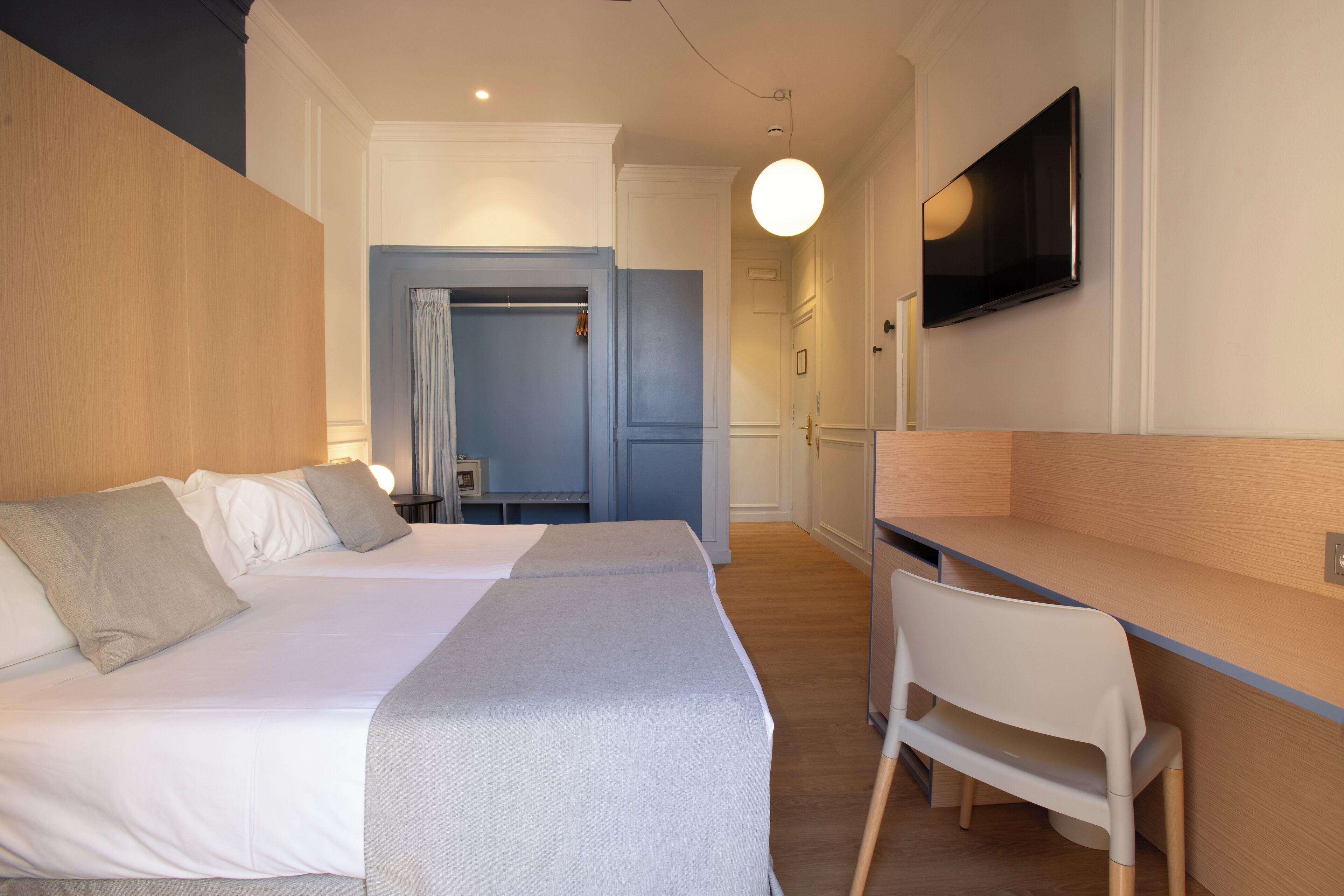 Una habitación de hotel con dos camas, un escritorio y una televisión.