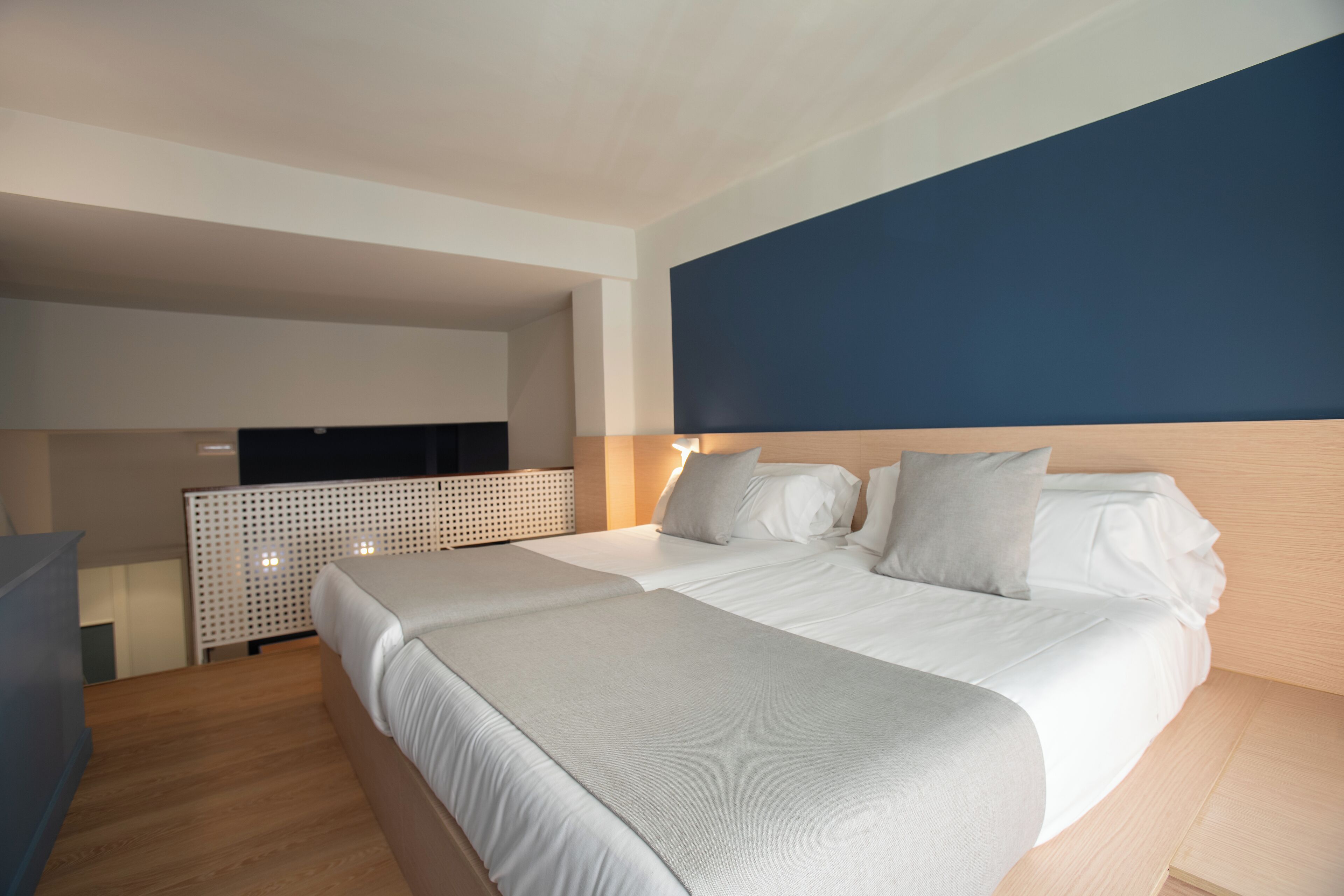 A modern hotel room with a large bed, a TV, and a wooden headboard.