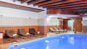 Zona de piscina con tumbonas de madera y un flotador en la pared.