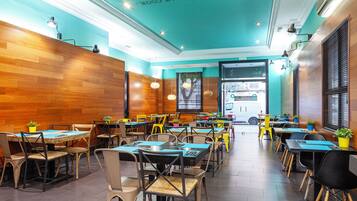 Interior de un restaurante con paredes de madera, varias mesas y sillas, y lámparas colgantes.