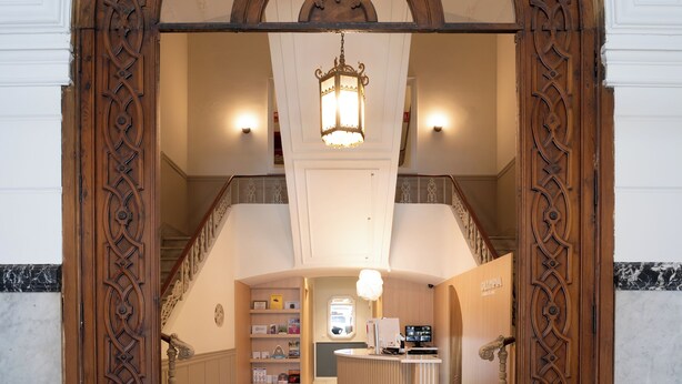 Un área de recepción con arco, una mesa de registro, una escalera y un mostrador de recepción.