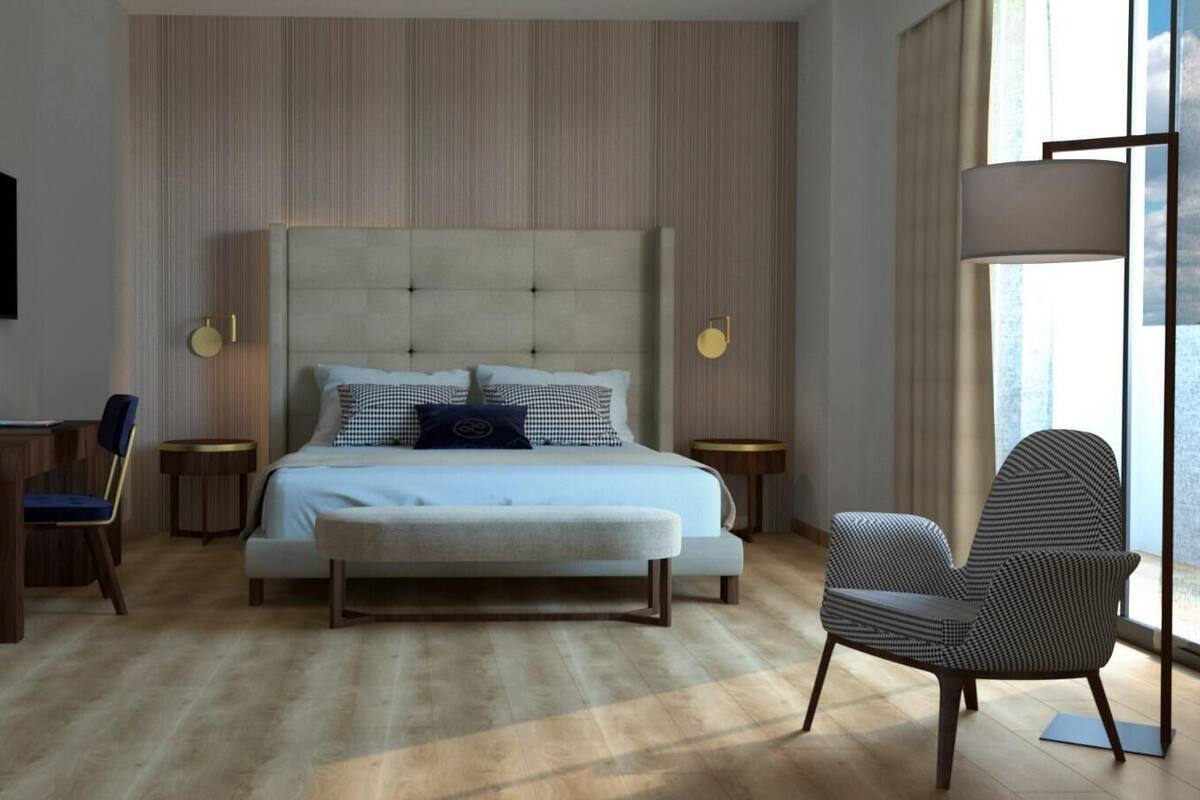 A modern hotel room with a large bed, a desk, a chair, and a sofa.