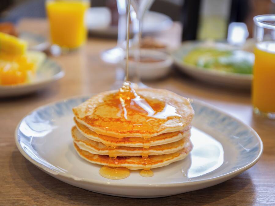 Una pila de tortitas con sirope en un plato.