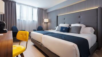 A hotel room with a large bed, two chairs, a desk, and a lamp.