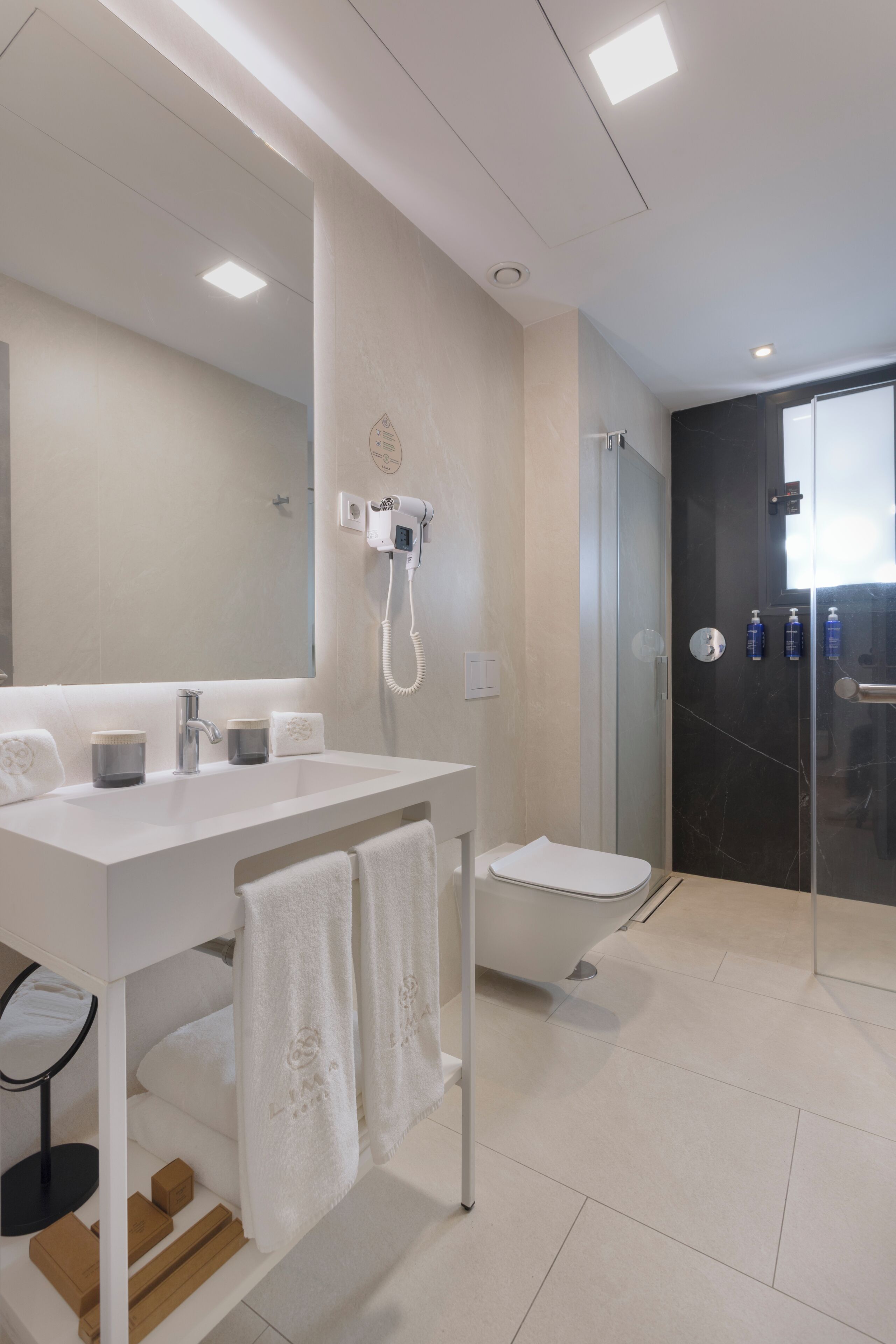 Une salle de bain moderne avec un lavabo blanc, un miroir et une cabine de douche en verre.