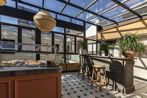 A modern kitchen with a glass ceiling, a dining area with stools, and potted plants. - Petit Palace Preciados (Madrid)