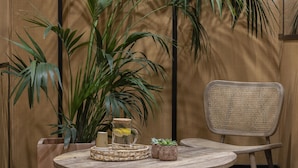 Una mesa redonda de madera con una cesta trenzada y pequeñas macetas.