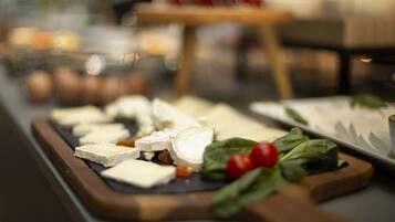 Una tabla de quesos con diferentes tipos de queso y hojas sobre una tabla de madera.