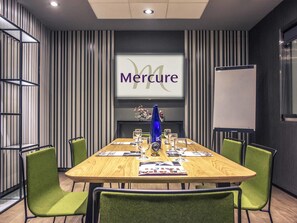 A conference room with a wooden table, green chairs, a whiteboard, and a screen displaying 'Mercure'. - Mercure Madrid Centro (Madrid)