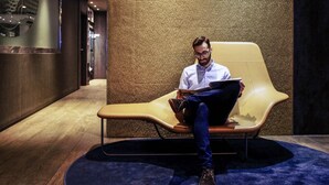 A man sitting on a modern lounge chair in a hallway with a textured wall and a sign that reads 'Mercure.' - Mercure Madrid Centro (Madrid)