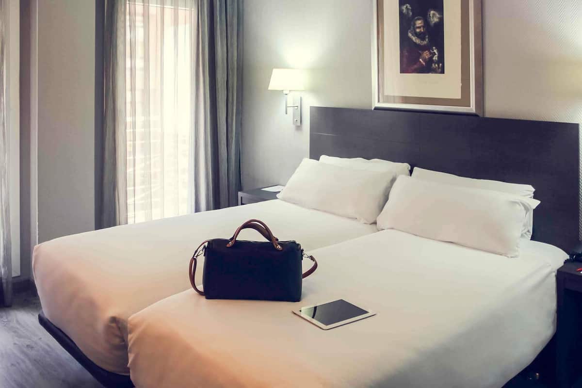 A hotel room with a large bed, a bedside table, a lamp, and a framed picture on the wall.