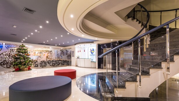 Un intérieur moderne avec un escalier en colimaçon, un sapin de Noël et un coin salon.