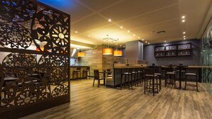 Un espace bar moderne avec un plancher en bois, des tabourets de bar et des luminaires suspendus.