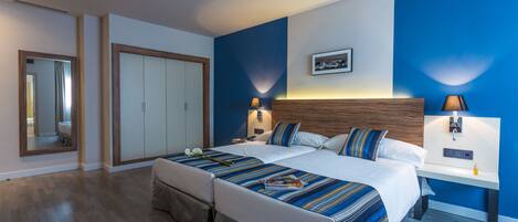 A double bed with a striped bedspread, a nightstand with a lamp, and a wardrobe.