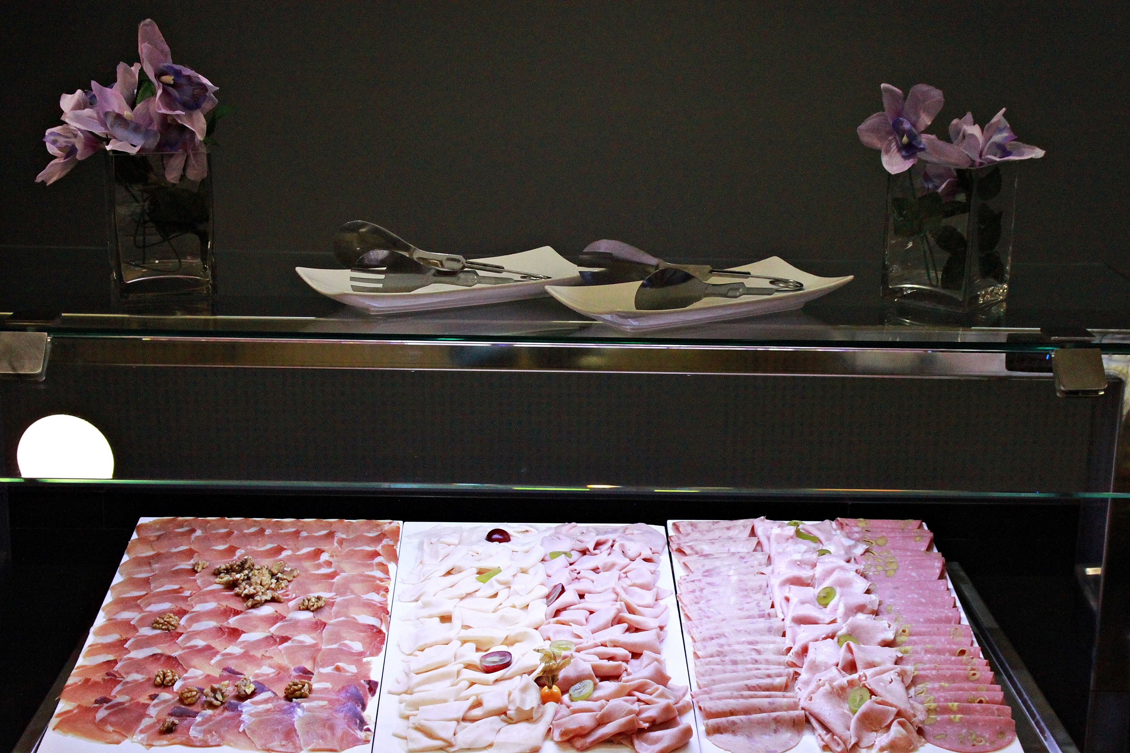 A display of food items in a glass case, including various meats and a plate with utensils.