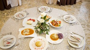 A round dining table with a floral centerpiece, surrounded by chairs with white napkins and silverware. - Tudanca Miranda (Miranda de Ebro)