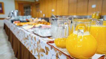Een buffet met verschillende gerechten en een karaf sinaasappelsap.