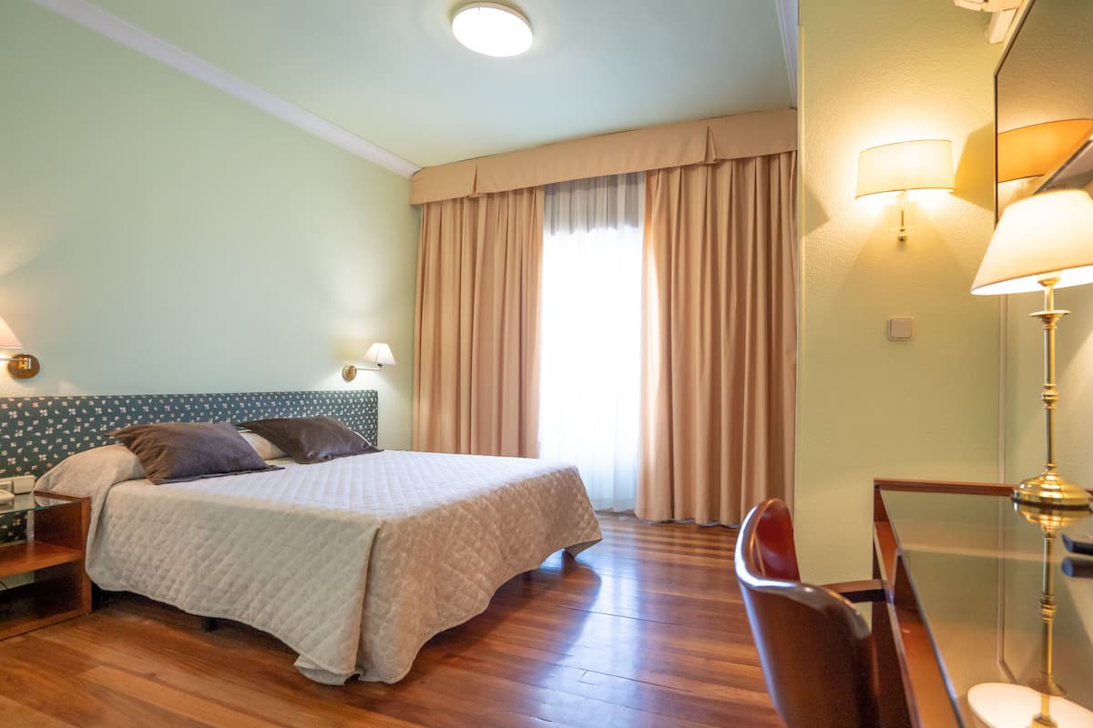 A hotel room with a bed, a desk, and a chair.