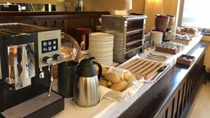 A buffet setup with a coffee machine, a cake display, and various food items. - Tudanca Miranda (Miranda de Ebro)