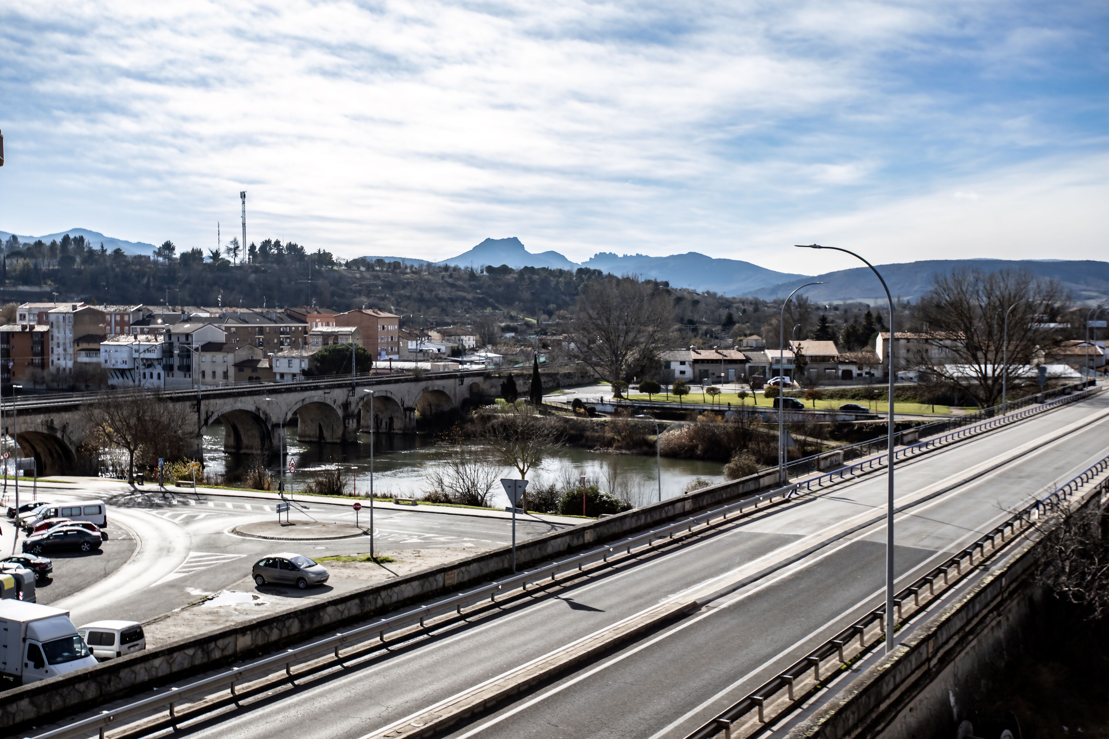 A highway overpass with a river and a bridge in the background.