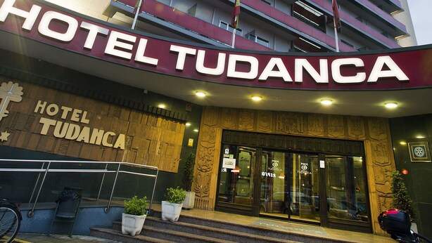 A hotel named 'TUDANCA' with a prominent sign, a staircase leading to the entrance, and potted plants at the base. - Tudanca Miranda (Miranda de Ebro)