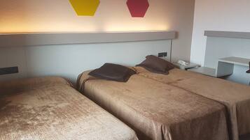 A hotel room with two beds, a bedside table with a phone, and a wall with hexagonal decorations.