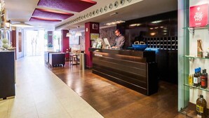 A hotel reception area with a wooden floor, a reception desk, and a bar area. - Hotel Xauen (Jaén)