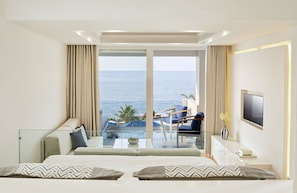 Ein modernes Hotelzimmer mit großem Balkon, einem Bett, einem Fernseher und Meerblick.