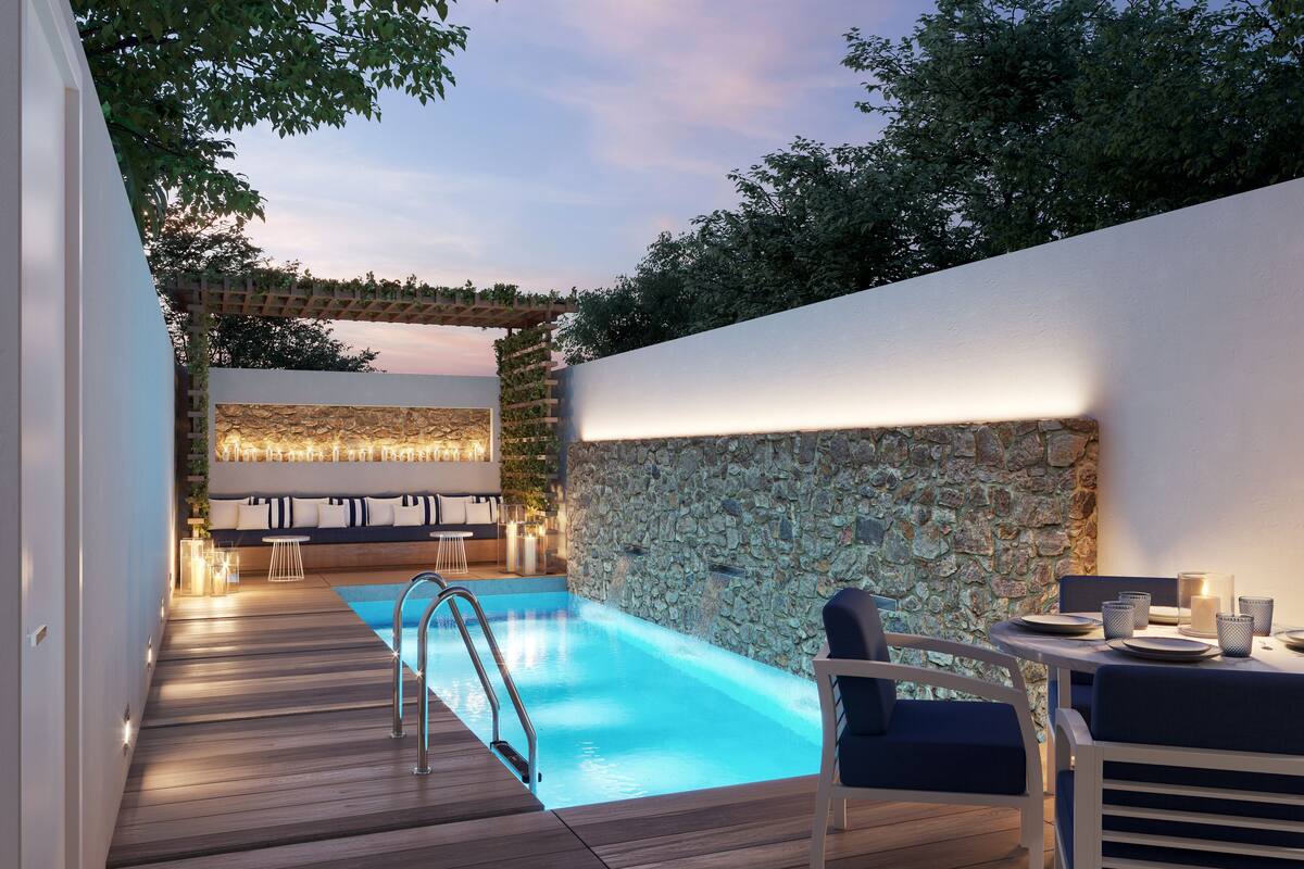 A modern outdoor pool area with a stone wall, wooden deck, and seating.