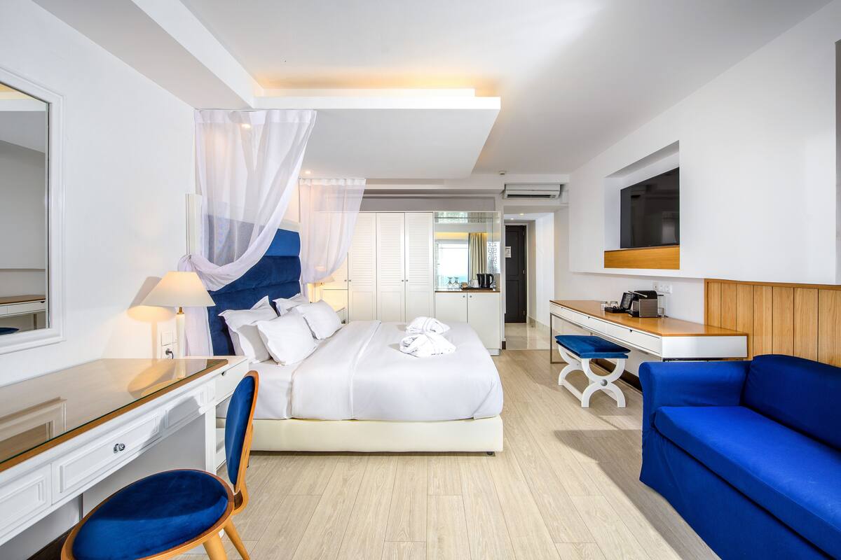 A hotel room with a bed, desk, chair, and a TV.