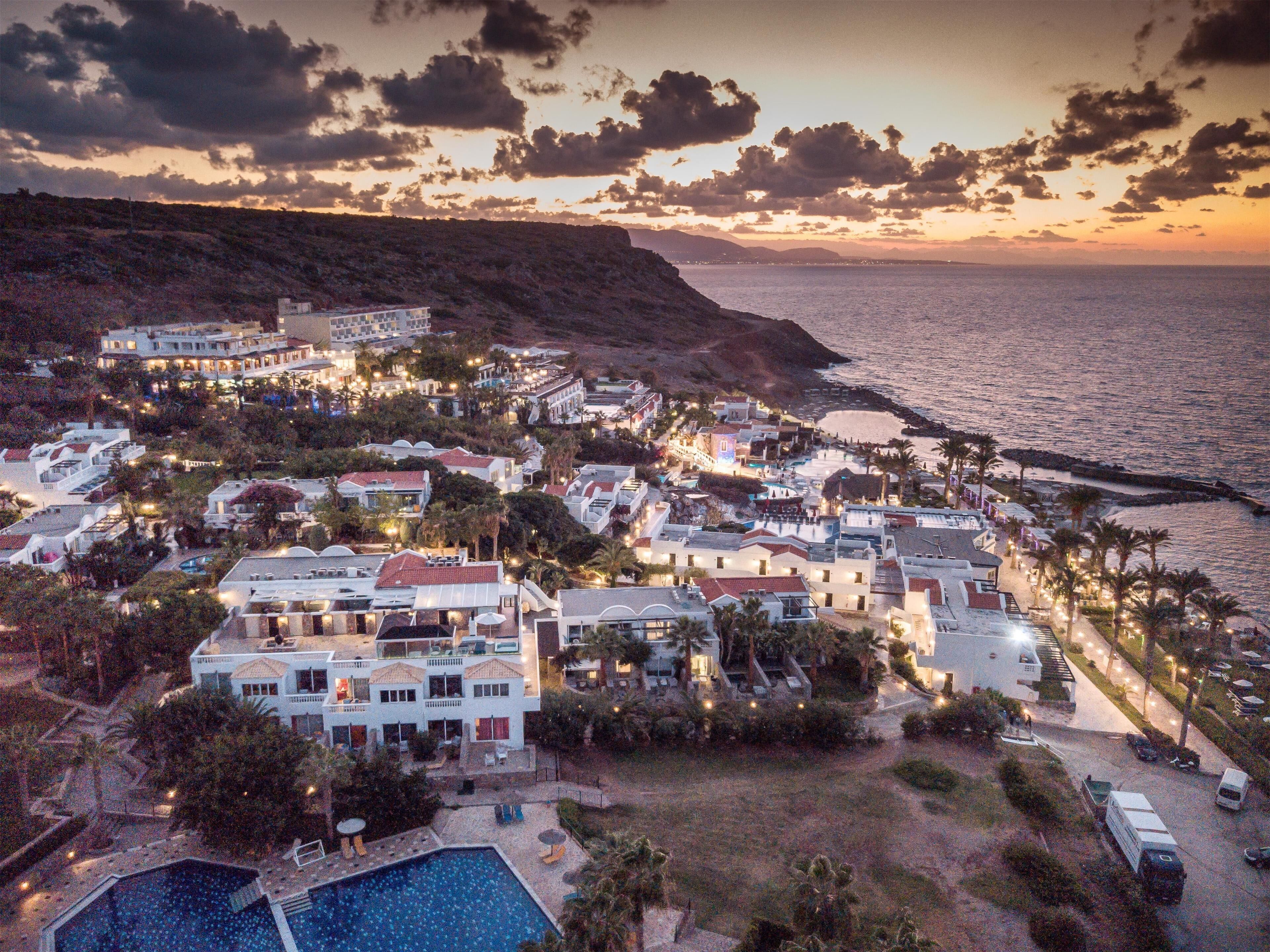 A coastal resort with multiple buildings, a swimming pool, and a beach.