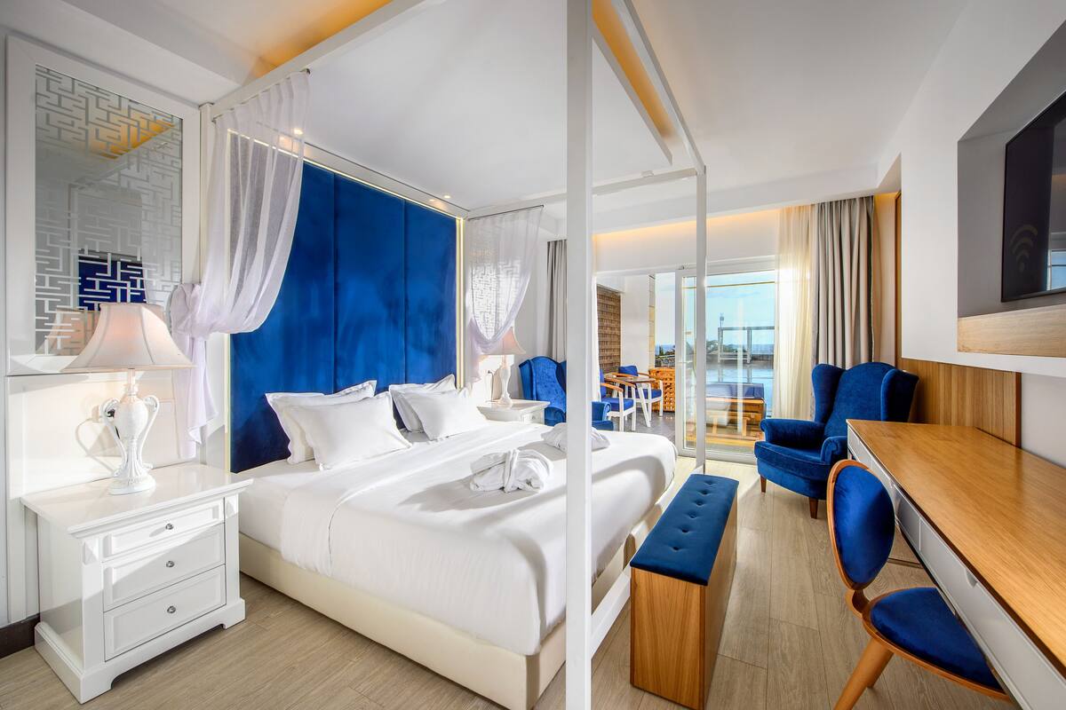 A modern hotel room with a large bed, a desk, and a view of the city.