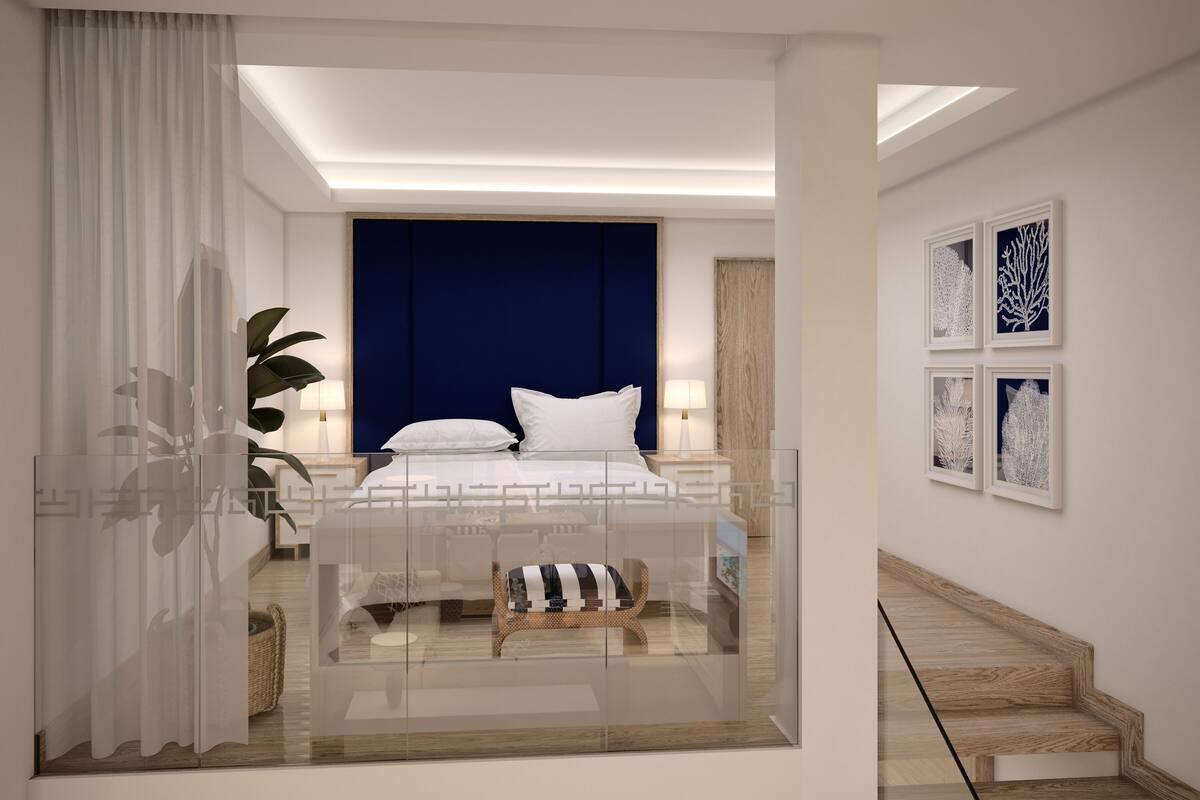 A modern bedroom with a large bed, bedside tables, a nightstand, a chair, and a staircase.