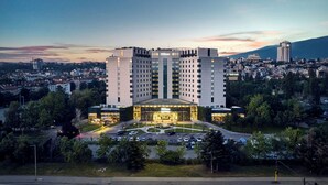 A multi-story hotel with a central entrance and a parking lot in front.