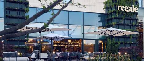 An outdoor seating area with umbrellas and chairs in front of a building with the sign "regale".