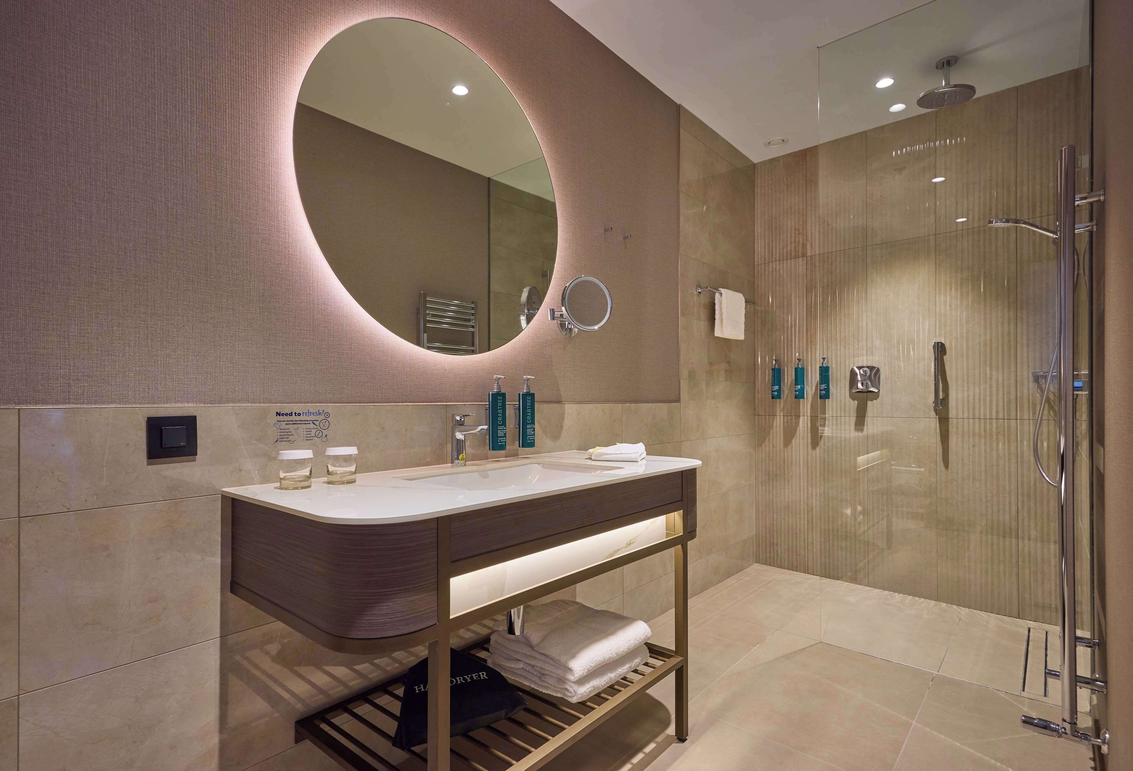 Un baño moderno con un espejo grande, un lavamanos y una ducha.
