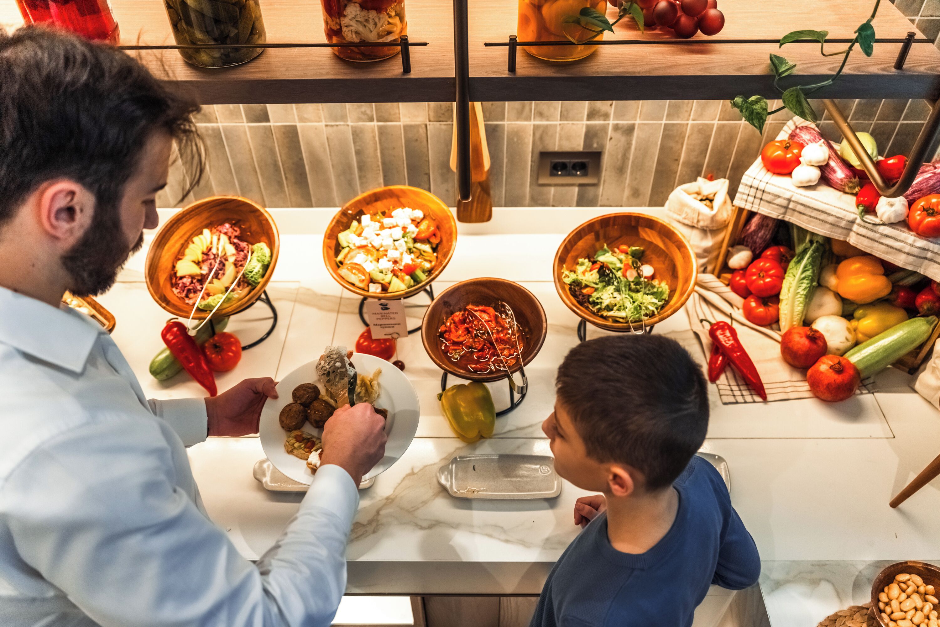 A kitchen with various bowls of food, a fruit basket, and a vegetable display.