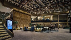A spacious lobby with a high ceiling, a staircase, and a seating area with sofas and chairs.
