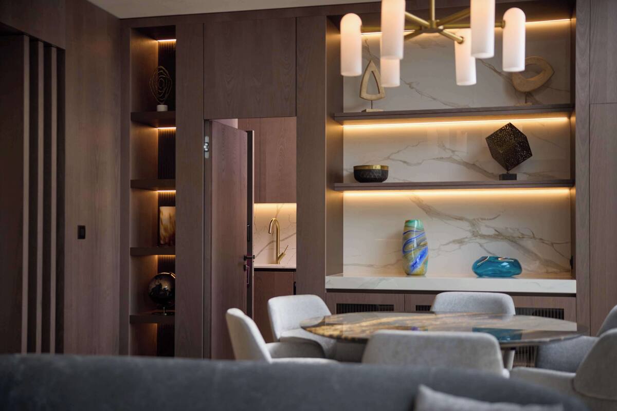 A modern dining area with a marble countertop, white chairs, and pendant lighting.