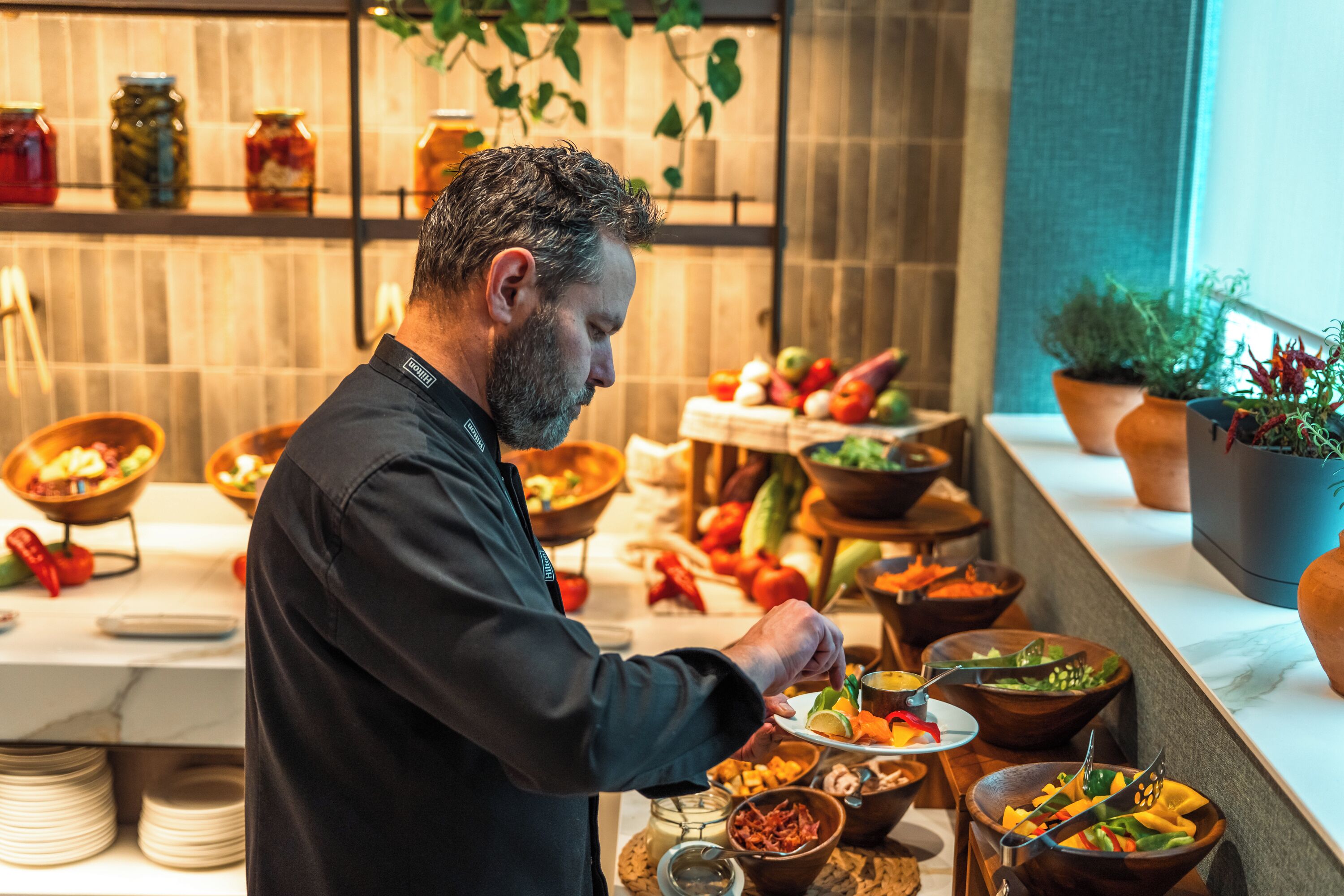 A buffet setup with various food items and a person serving.