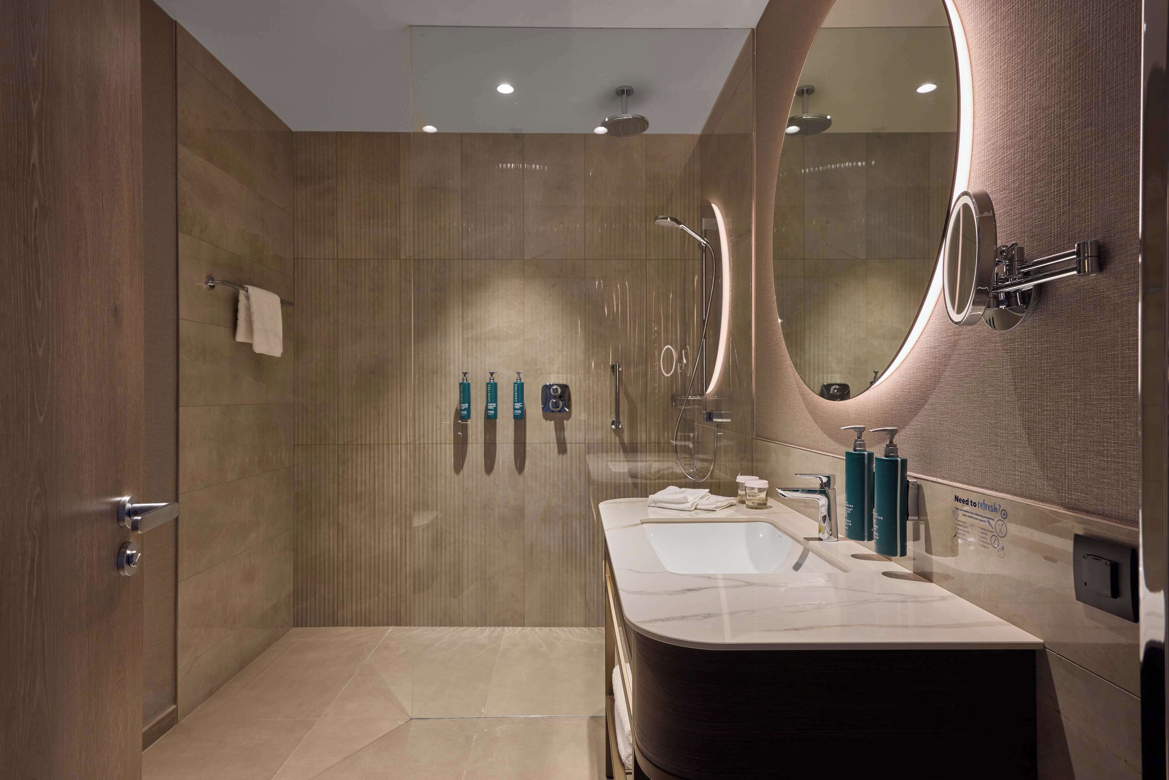 A modern bathroom with a large mirror, a bathtub, and a shower area.