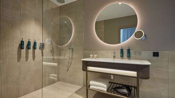A modern bathroom with a glass shower enclosure, a vanity with a mirror, and toiletries.