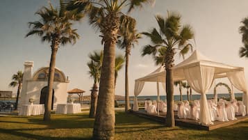 A wedding venue with a tent, palm trees, and a building with a dome.