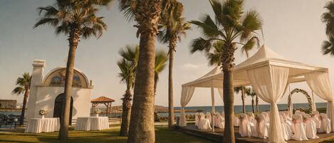 A wedding venue with a tent, palm trees, and a building with a dome.