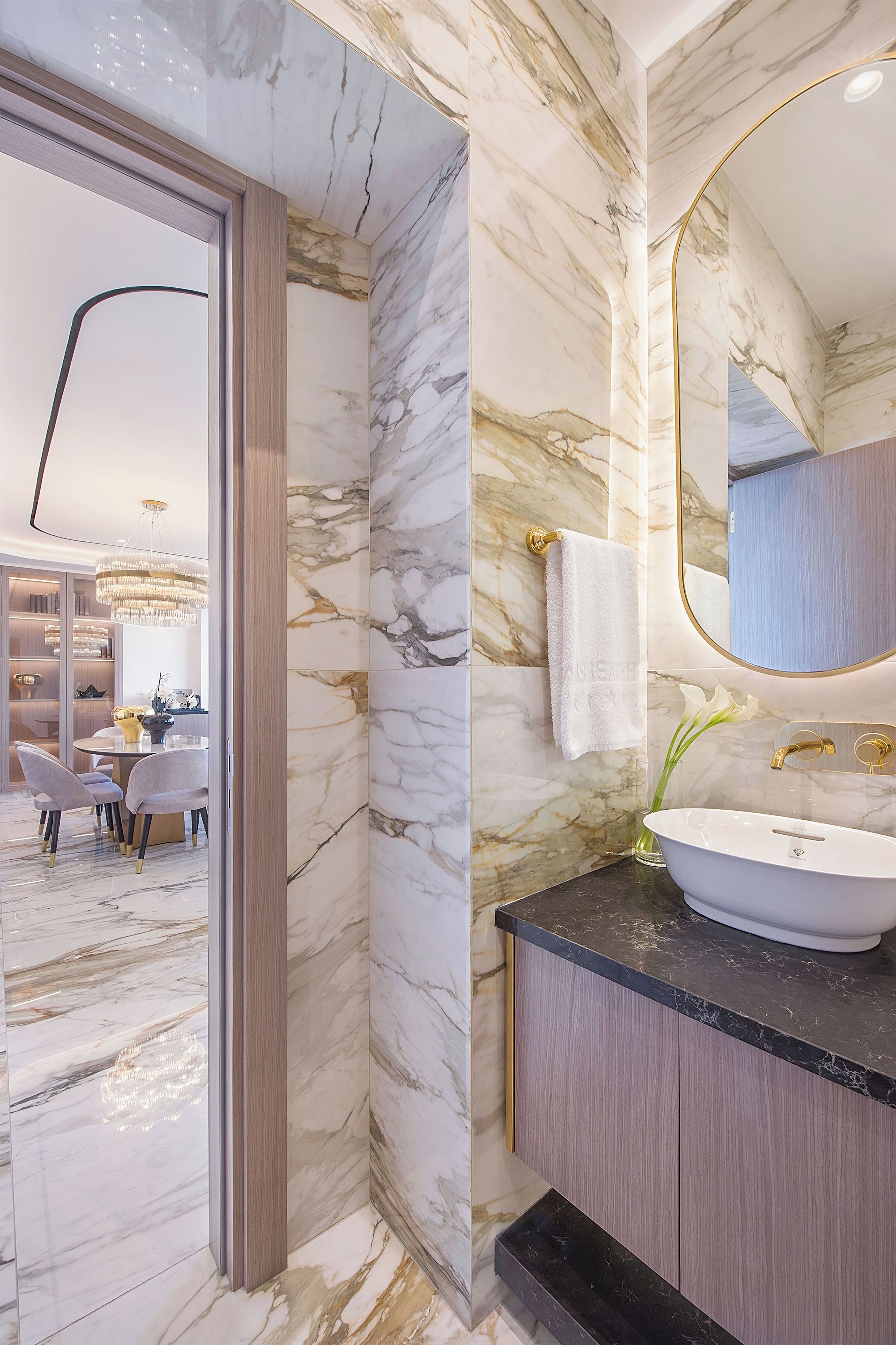 Une salle de bain moderne avec des murs en marbre, un grand miroir et un lavabo blanc.