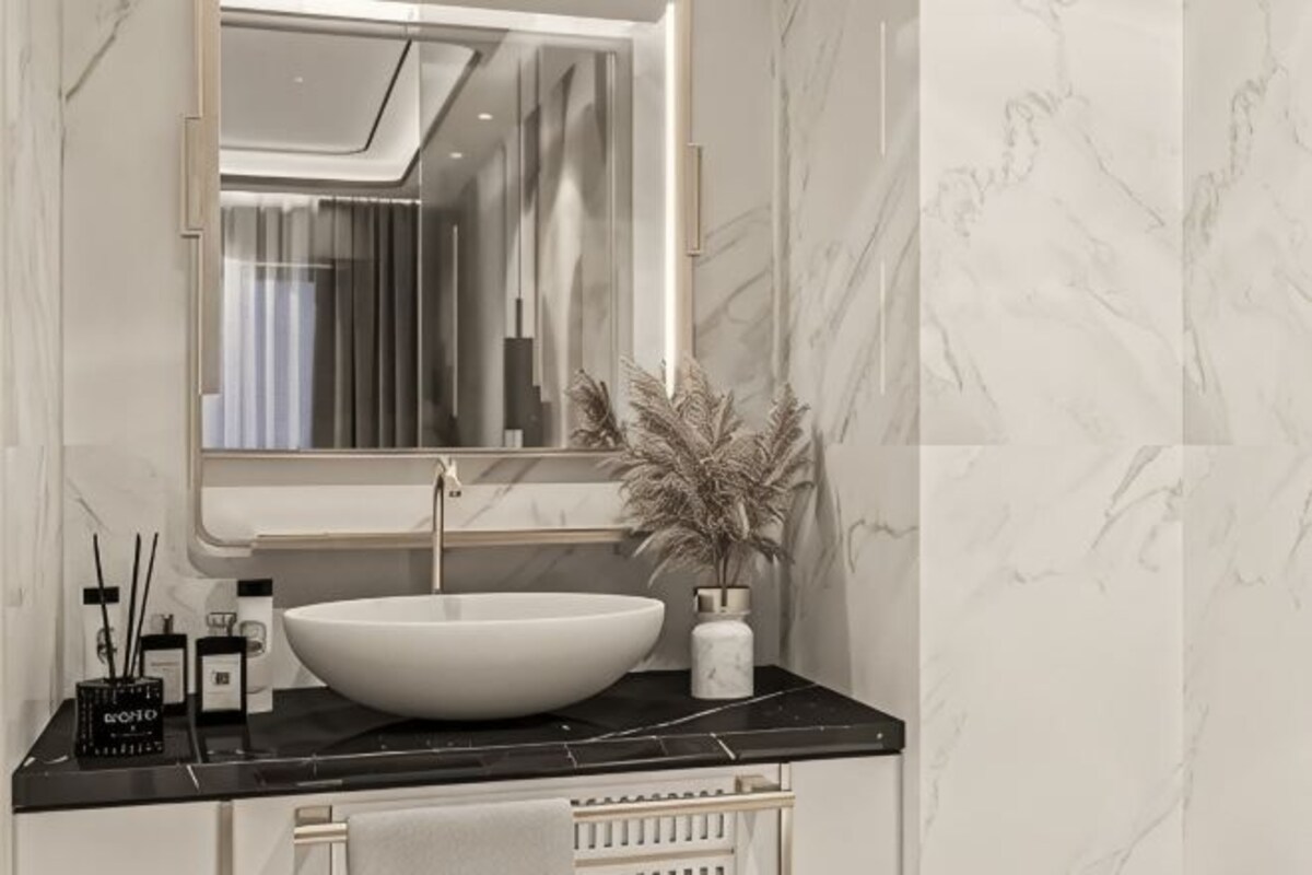 A bathroom with a white vessel sink, a mirror, and a vase with dried flowers.